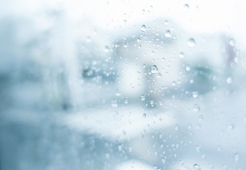窓ガラスに付着した雨粒と曇り空
