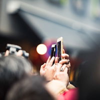 スマートフォンを掲げて撮影する人混み、イベントや記者会見の群衆の写真