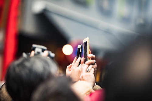 スマートフォンを掲げて撮影する人混み、イベントや記者会見の群衆