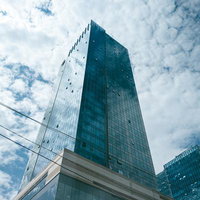 青空と雲を背景にした現代的なガラス張り高層オフィスビルの写真