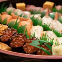 黒い丸皿に盛り付けた宅配寿司の盛り合わせの写真