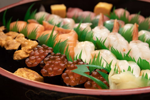 黒い丸皿に盛り付けた宅配寿司の盛り合わせ