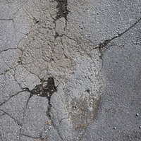 アスファルトの地面に残るひび割れたテクスチャーの写真