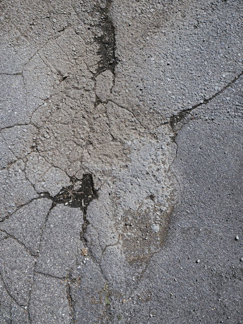 アスファルトの地面に残るひび割れたテクスチャー