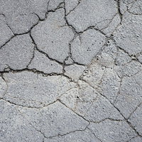 ひび割れが広がるアスファルトの地面テクスチャーの写真