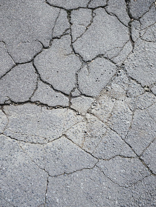 ひび割れが広がるアスファルトの地面テクスチャー