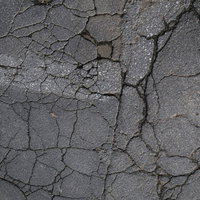 ひび割れたアスファルトに残る白い跡（テクスチャー）の写真