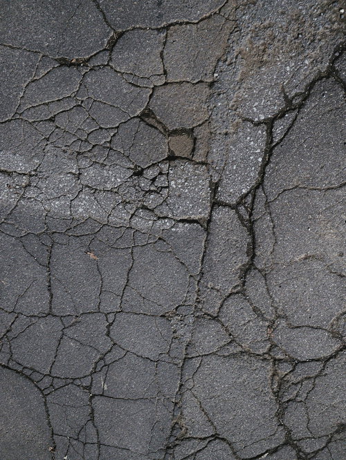 ひび割れたアスファルトに残る白い跡（テクスチャー）