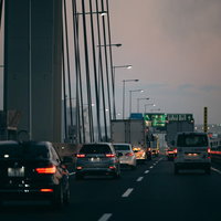 夕暮れの高速道路を走る車の後ろ姿と連なる車列の写真
