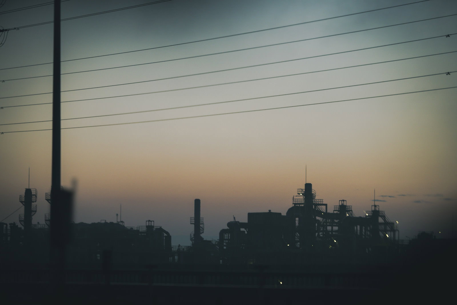 夕焼け空を背景にした工場群と電線のシルエット
