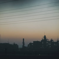 夕暮れと工場のシルエット：電線と煙突が映える夕焼けの都市風景の写真