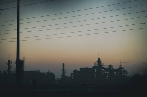 夕暮れと工場のシルエット：電線と煙突が映える夕焼けの都市風景
