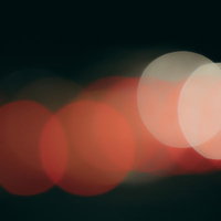 暗闇に連なる赤い光源と玉ボケの夜景背景の写真