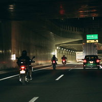 高速道路での夜間走行するバイクと自動車のテールランプの写真