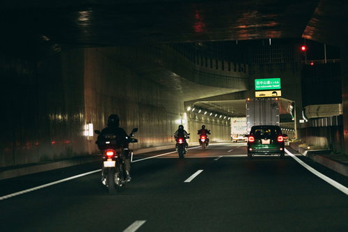 高速道路での夜間走行するバイクと自動車のテールランプ