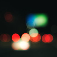 赤いテールランプと街の光が丸くボケた夜景の写真