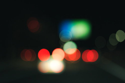 赤いテールランプと街の光が丸くボケた夜景