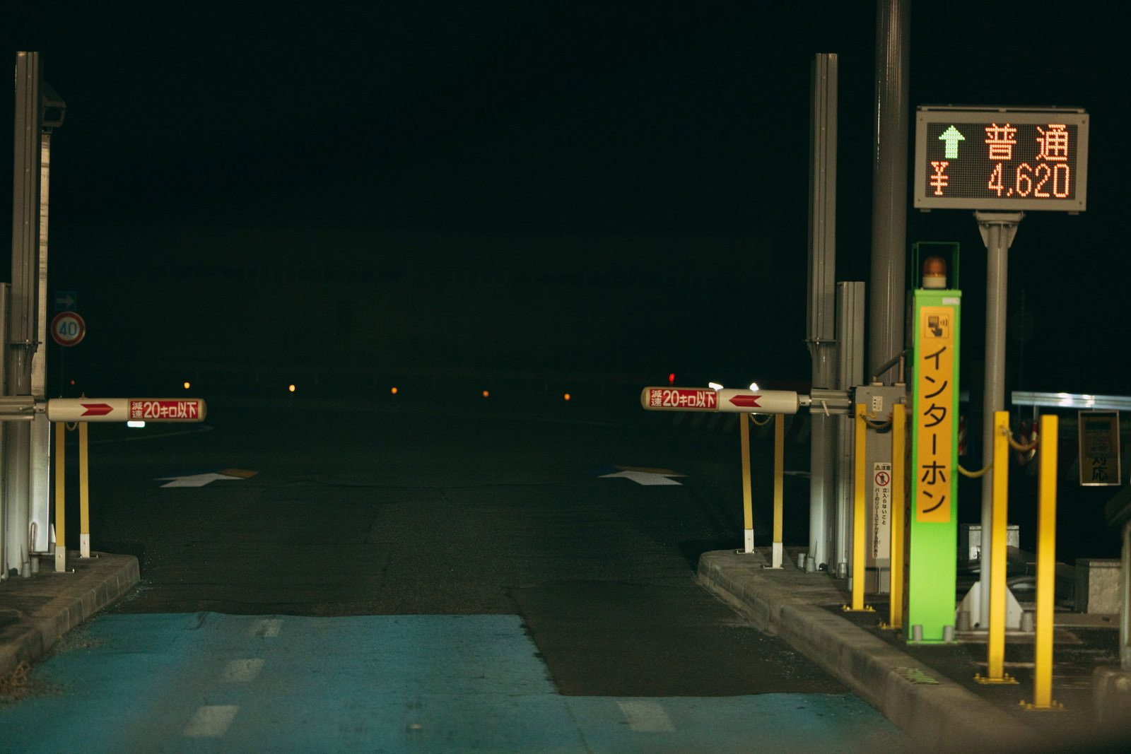 夜の高速道路料金所でETCゲートのバーと案内表示が照明で照らされている