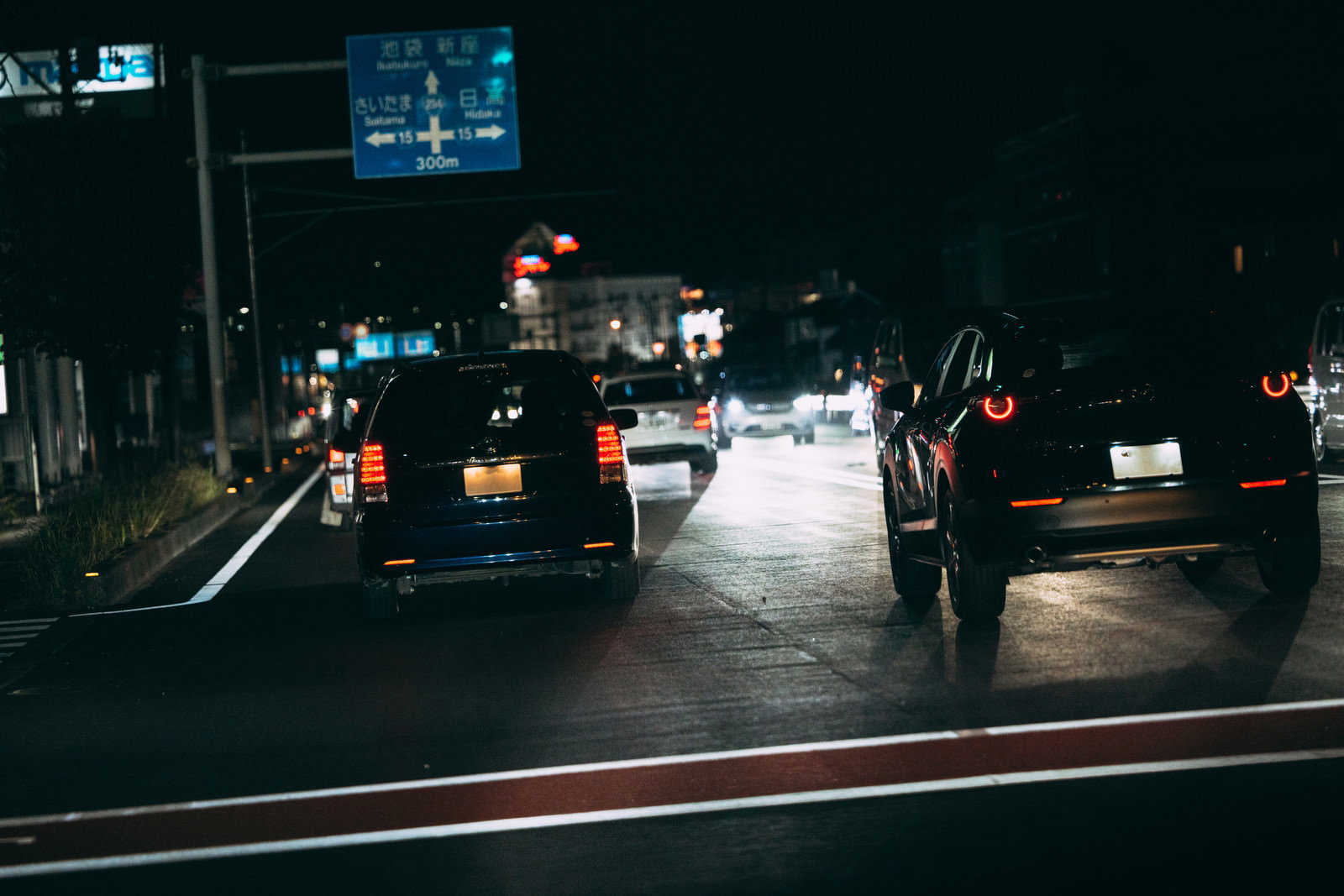 対向車のハイビームが眩しい夜間の道路で前方車両のテールランプが光る様子
