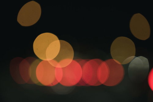 暗闇に舞うオレンジ色のボケと玉ボケ、温かい光の背景