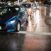 雨の夜道に停車する自動車の写真