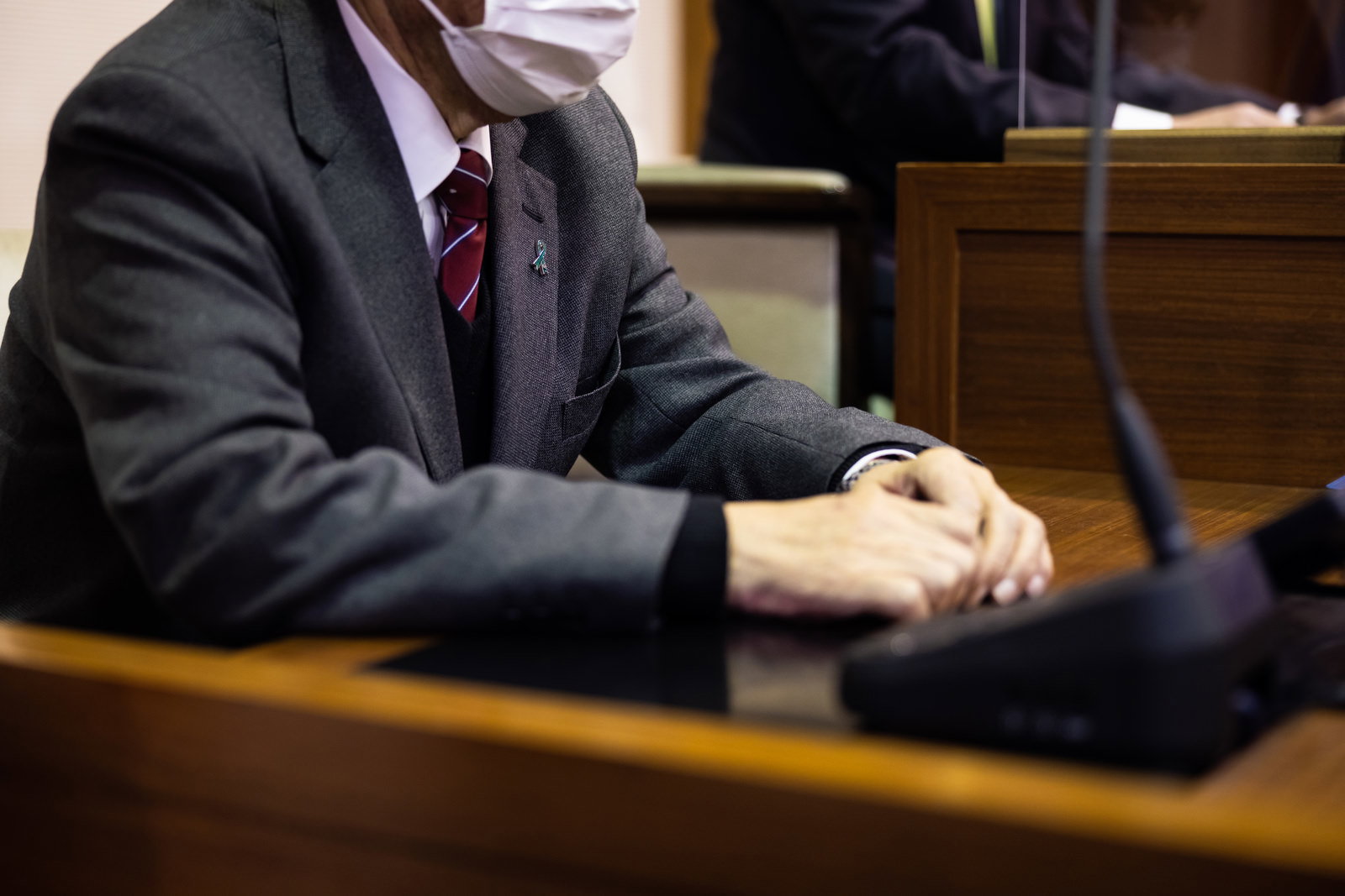 議会の事務局長席に座るマスク姿の男性
