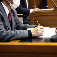 議場で鉛筆でメモを取る市議会議員の本会議風景の写真