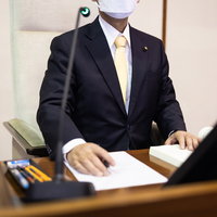 議場内の最高位に設置された議長席で書類を確認する男性議員の写真