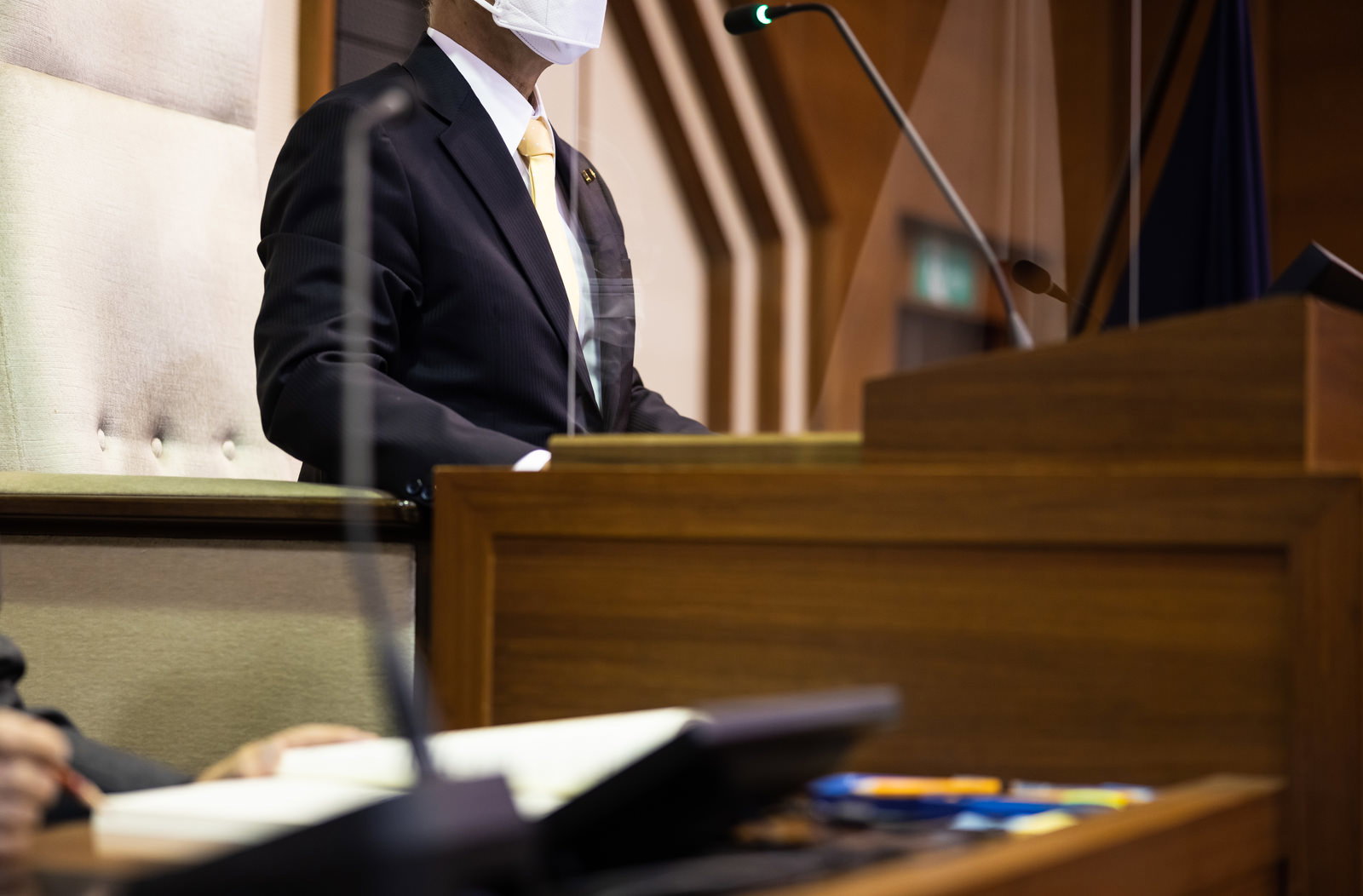 マスクを着用した議長が議長席で市議会の議事を進めている