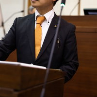 紙原稿を見ながら議会で質問する議員の登壇風景の写真