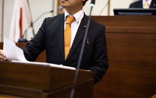 紙原稿を見ながら議会で質問する議員の登壇風景