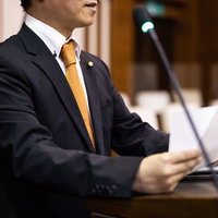 紙原稿を手に熱弁する市議会議員、議場で発言の写真