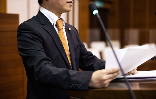 紙原稿を手に熱弁する市議会議員、議場で発言