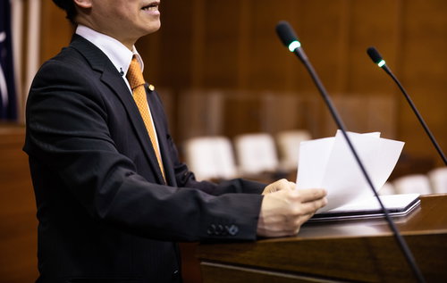 議員バッジをつけて市議会で熱弁する市議会議員の演説風景