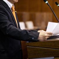 議会で原稿を読みながら演説する市議会議員の写真