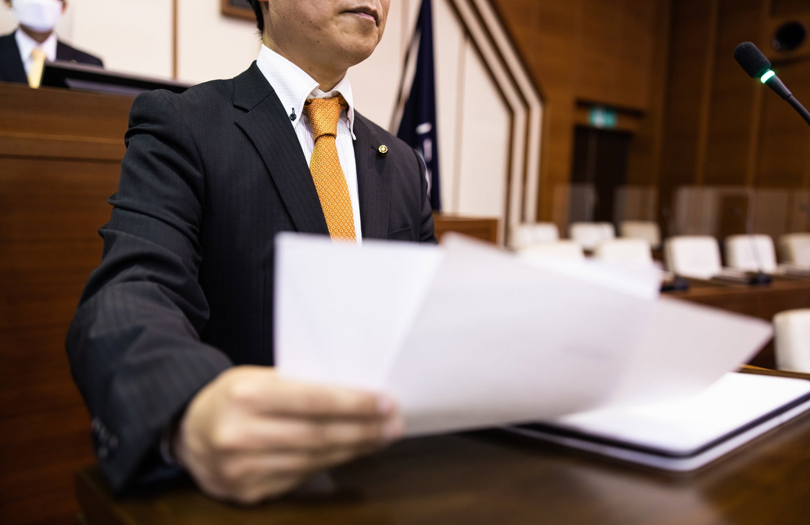 議場で原稿を持って発言する男性議員の姿