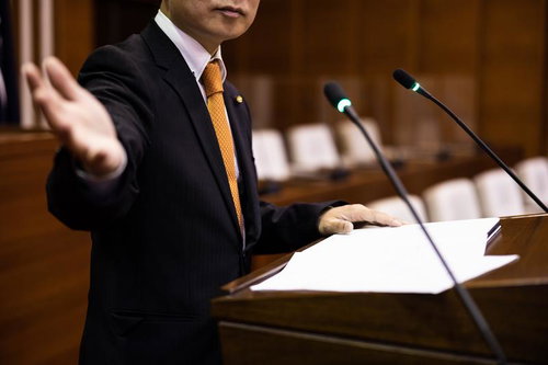 手を広げて意見を述べる市議会議員の登壇演説