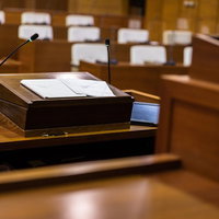 登壇席に置かれたタブレット端末と紙原稿、マイクの写真