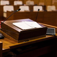 津山市議会議場の木製演壇に置かれた資料とマイクシステムの写真