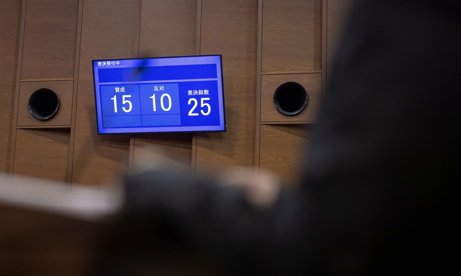 青い電光板に表示された市議会の採決結果。賛成15票、反対10票、表決総数25
