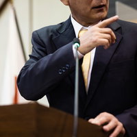 市議会の議場で厳しく追及する議員の質問登壇シーンの写真