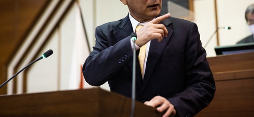 市議会の議場で厳しく追及する議員の質問登壇シーン