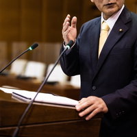 登壇席で市議会の市長と向き合いながら熱く語る議員の写真