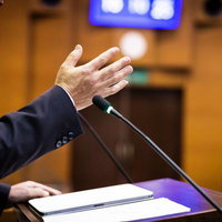 採決に関して議論する市議会議員、マイク前で演説の写真