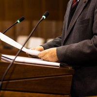 津山市議会本会議場で演壇に立つスーツ姿の男性議員の写真
