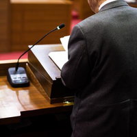 津山市議会の演壇で答弁する男性議員の後ろ姿の写真