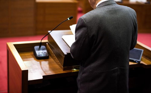 津山市議会の演壇で答弁する男性議員の後ろ姿