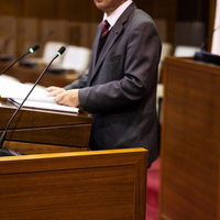 本会議場の演壇でマイクに向かう市議の写真