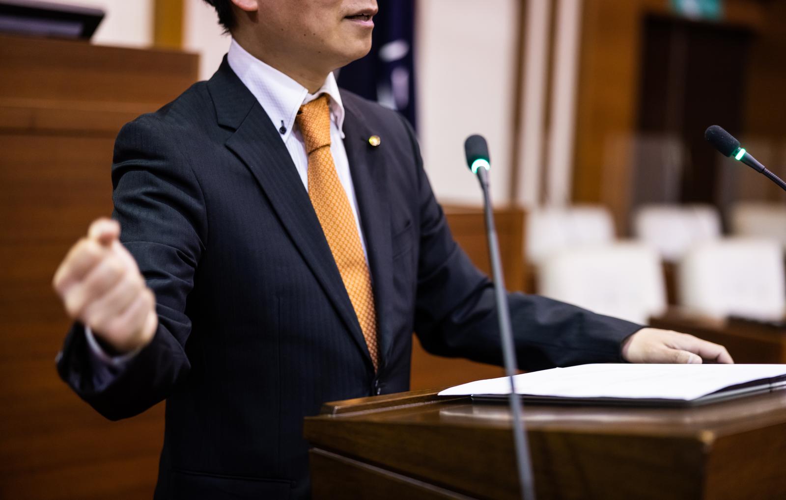 市議会の議場で両拳を握ってガッツポーズする政治家