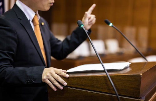 人差し指を立てて市議会で説明する議員の熱弁